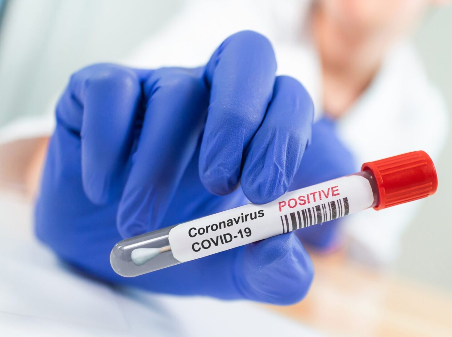 COVID-19 positive test tube in gloved hand.