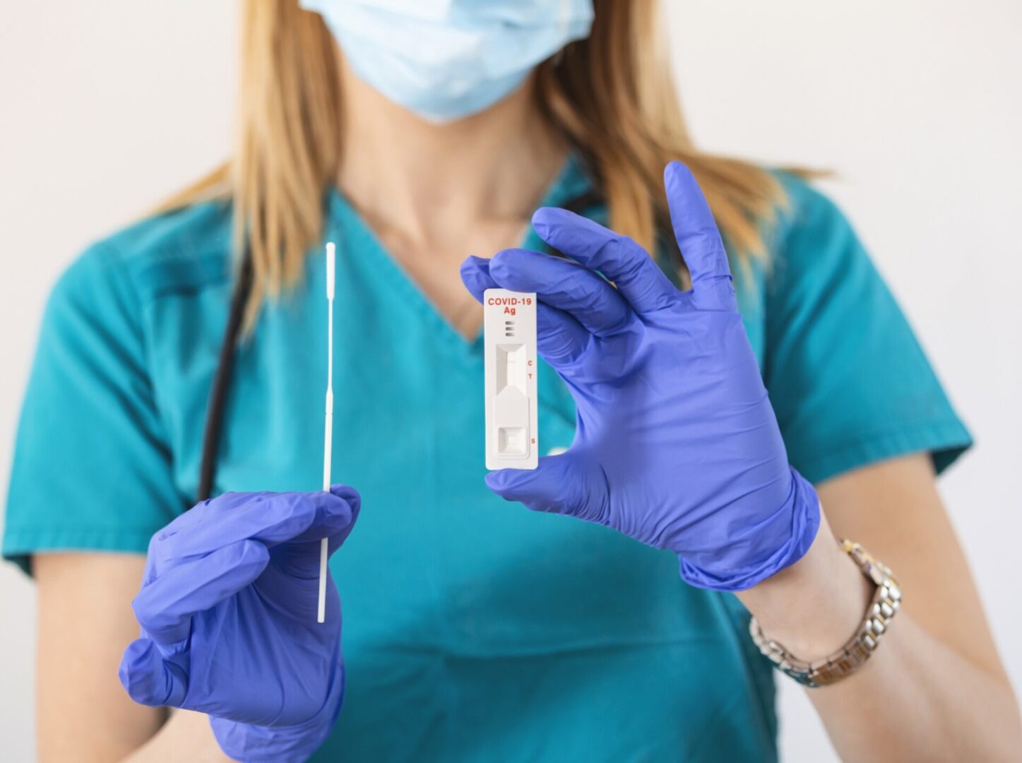 Healthcare worker holding COVID-19 test kit.