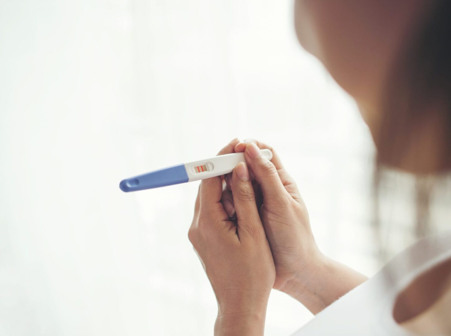 Person holding a pregnancy test indoors.