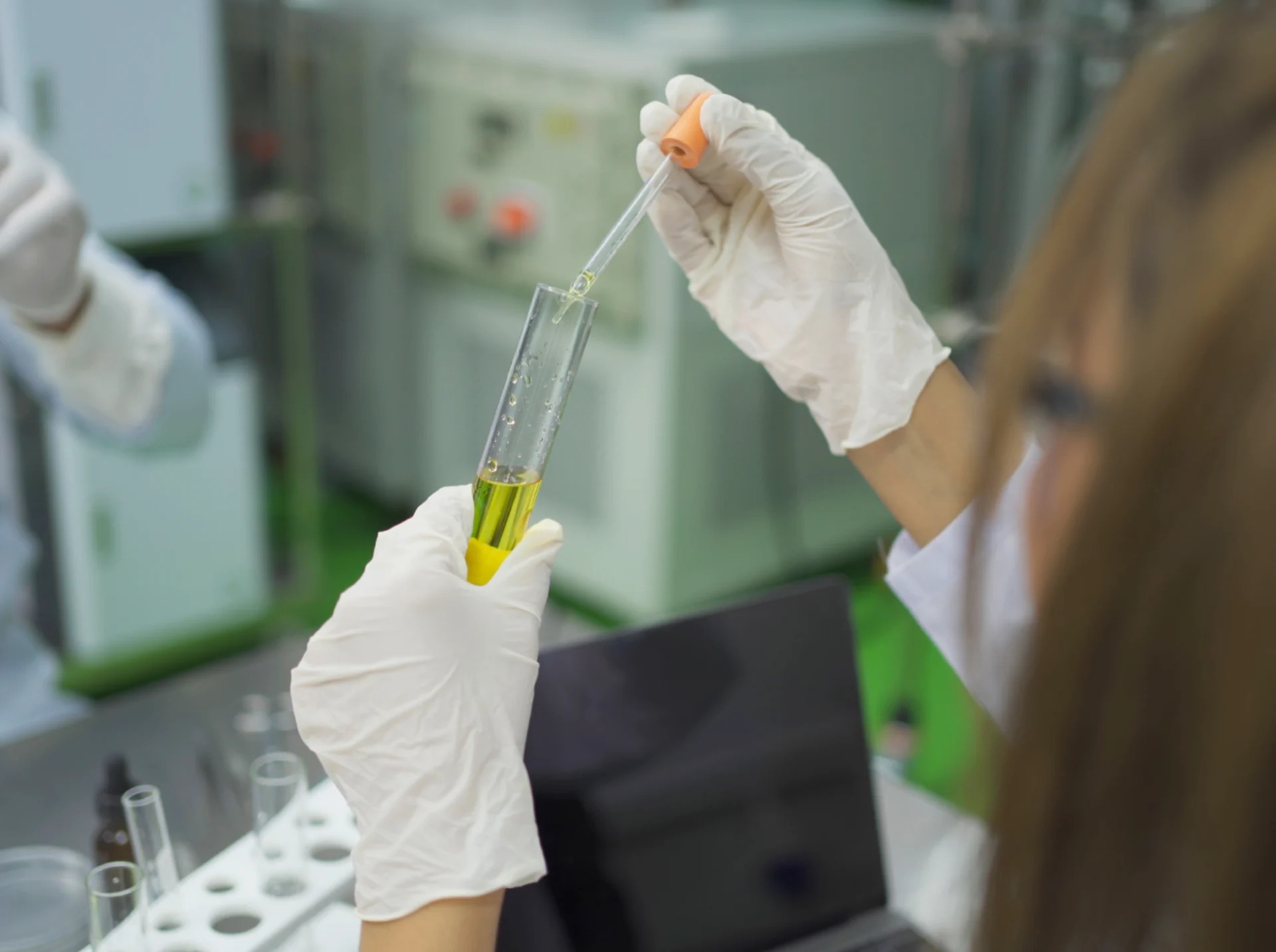 Scientist handling yellow liquid in test tube.