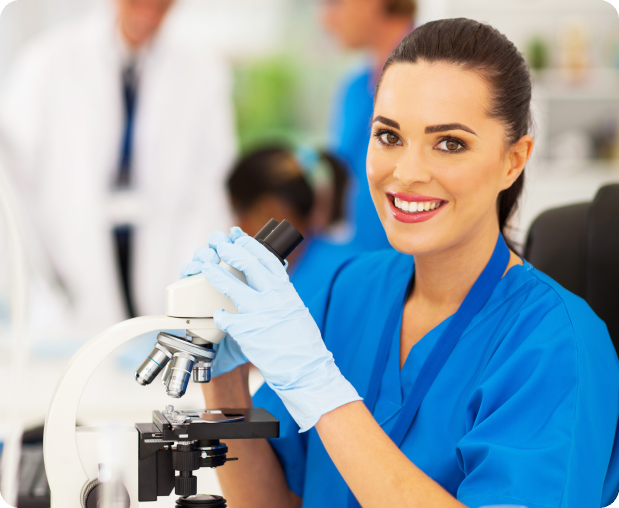 Smiling scientist in blue gloves using a microscope in a lab.