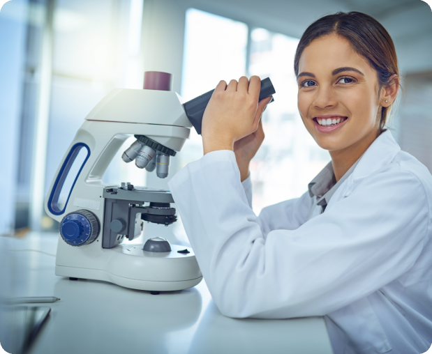 Smiling scientist with microscope in lab.