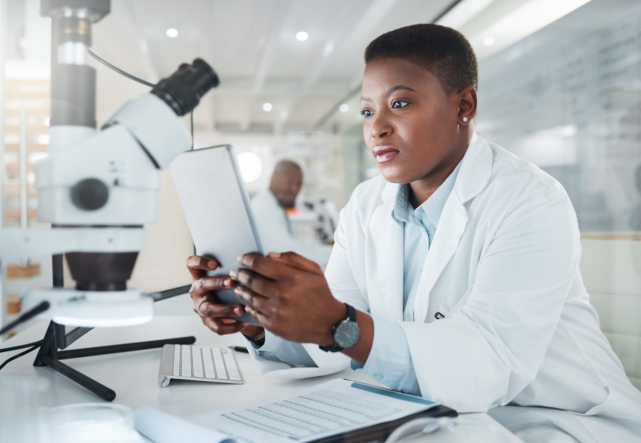 Scientist reviewing data on a tablet in a modern lab.