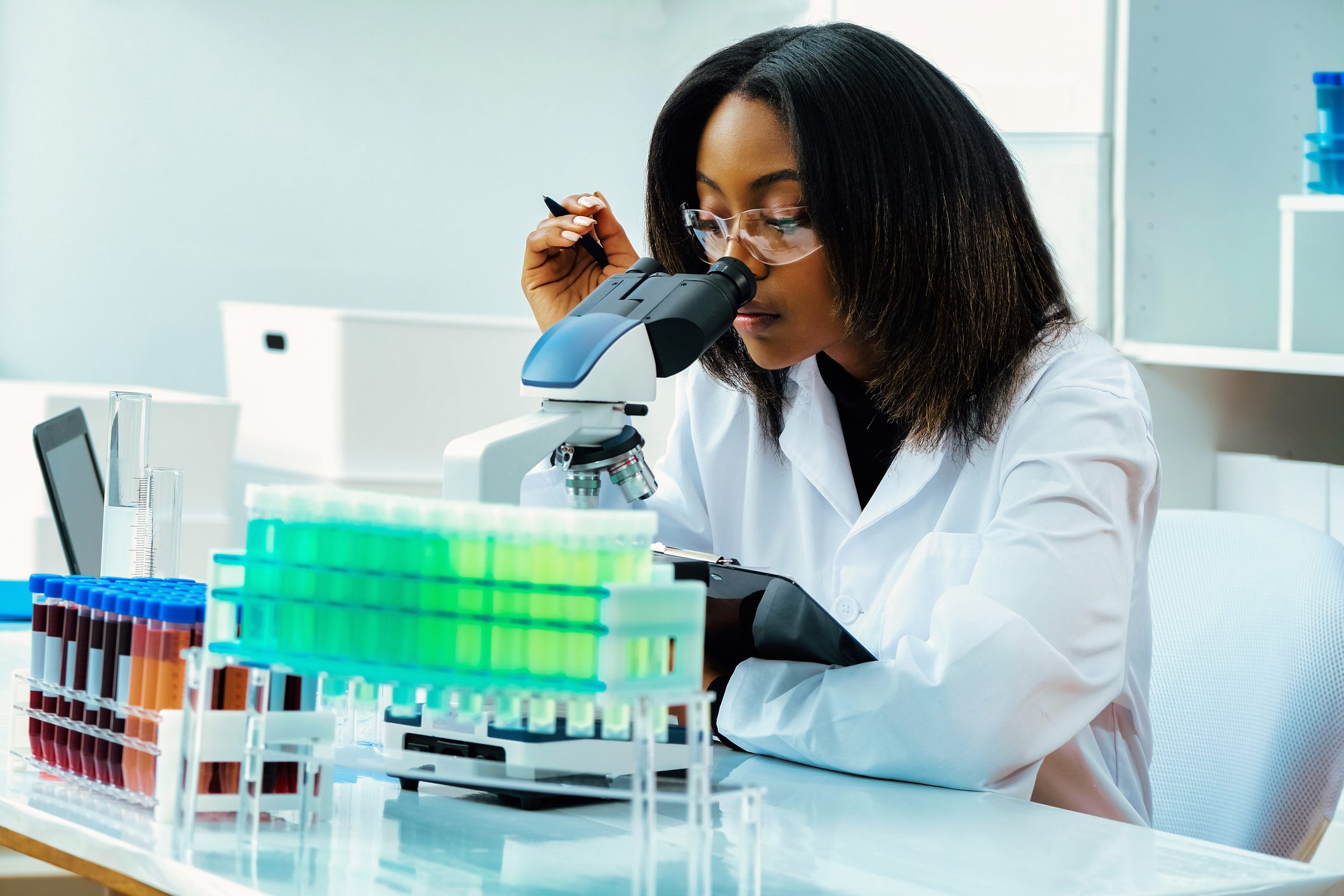 Scientist examining samples under a microscope in a lab.