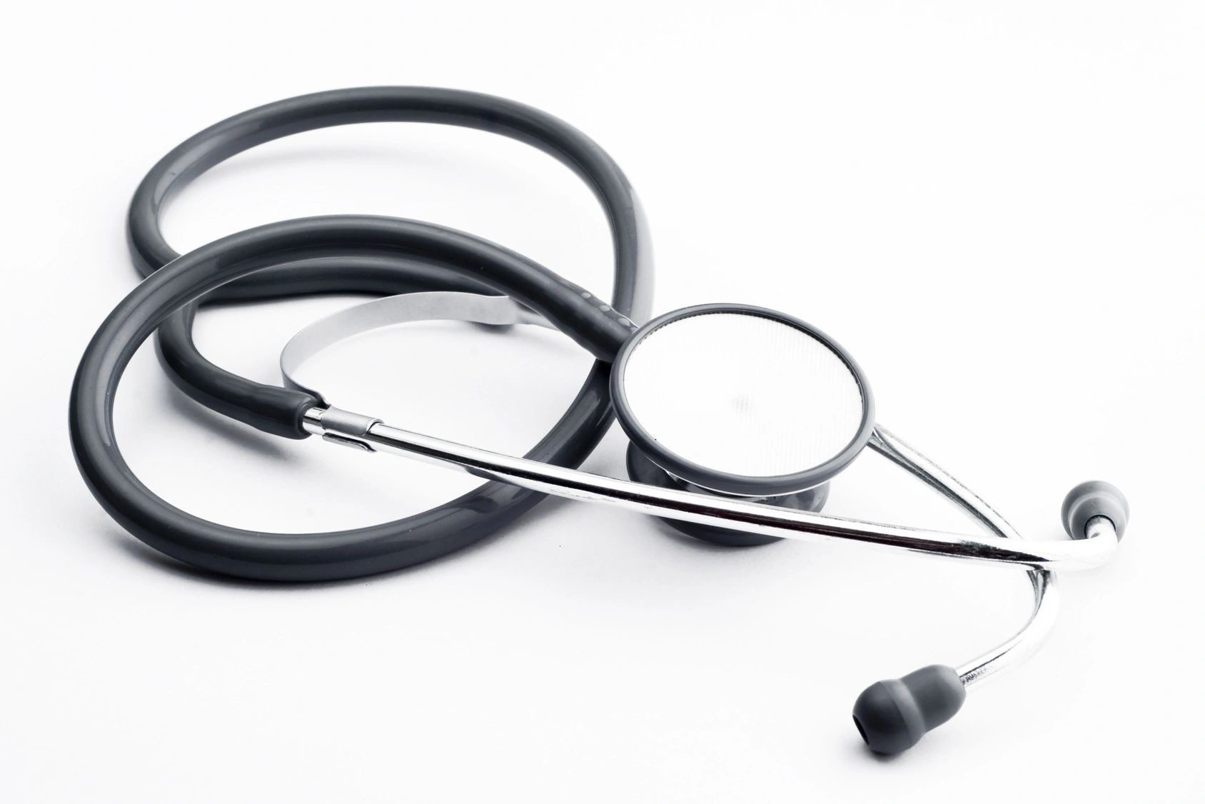 Close-up of a black stethoscope on a white surface.